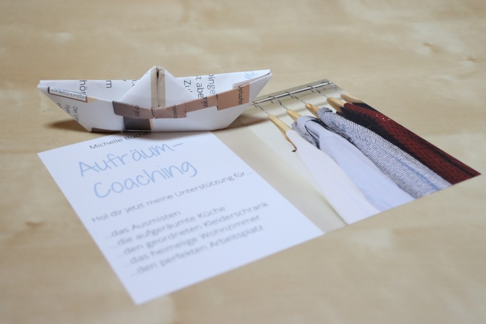 Ein Flyer wurde zu einem Origami-Schiffchen gefaltet und schwimmt auf dem Originalflyer